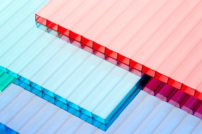 Brightly colored plastic sheets with hollow cells stacked unevenly.