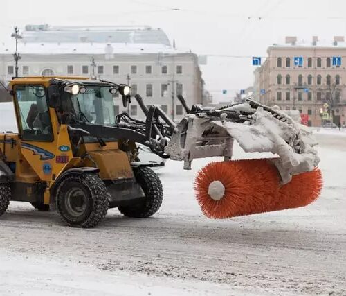 Mechanical snow broom operates on a snowy downtown street