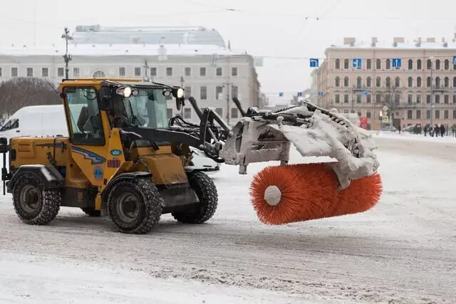 Mechanical snow broom operates on a snowy downtown street