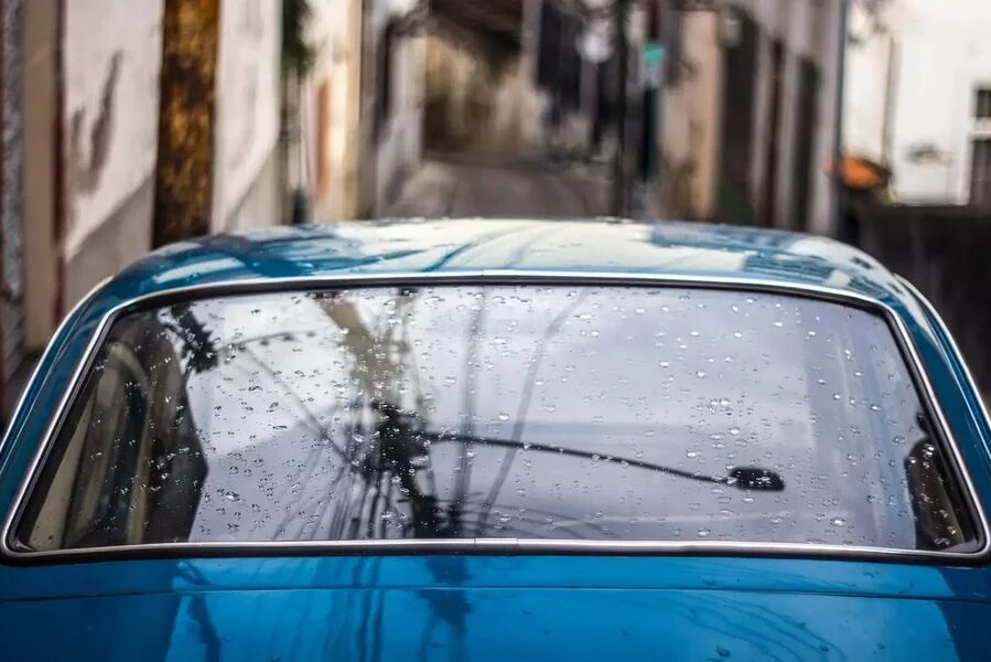 Car with water on its back windshield going through an automatic car wash