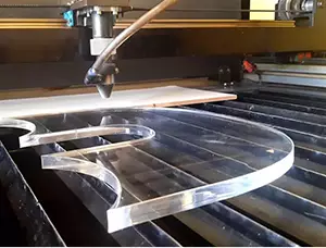 CNC machine cutting a clear piece of plastic.